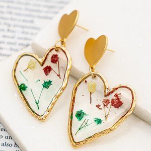 Clear heart shape resin earrings with dried flowers inside.